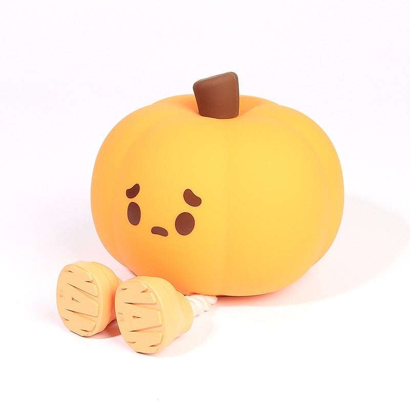 Small silicone pumpkin night lamp with cute facial expression and dangling legs, perfect for Halloween-themed ambient lighting and gifts.