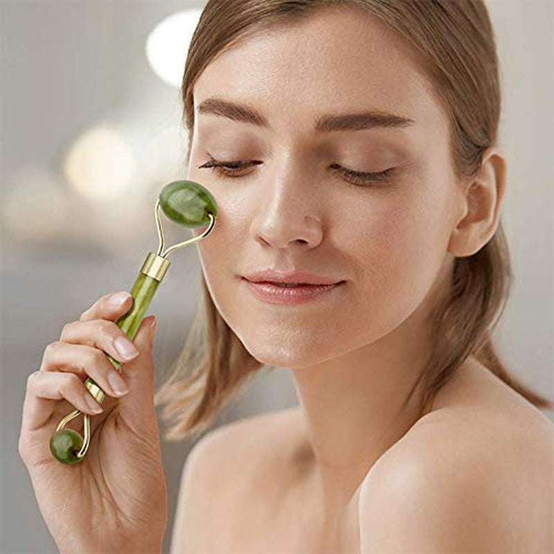 Woman using jade roller facial tool under eye area to reduce puffiness and fine lines, promoting youthful skin appearance.